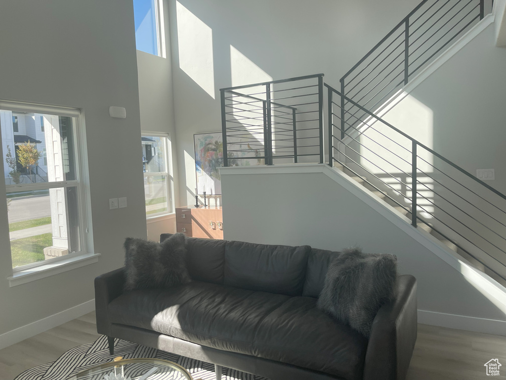 Living room with a high ceiling, wood finished floors, baseboards, and stairway