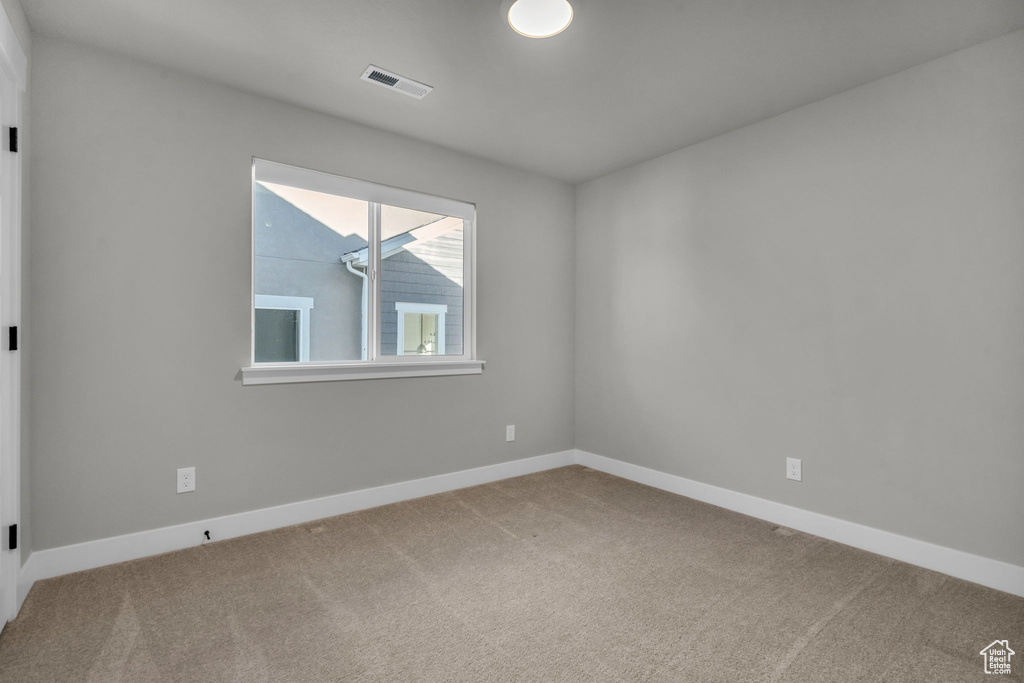 Carpeted empty room featuring visible vents and baseboards