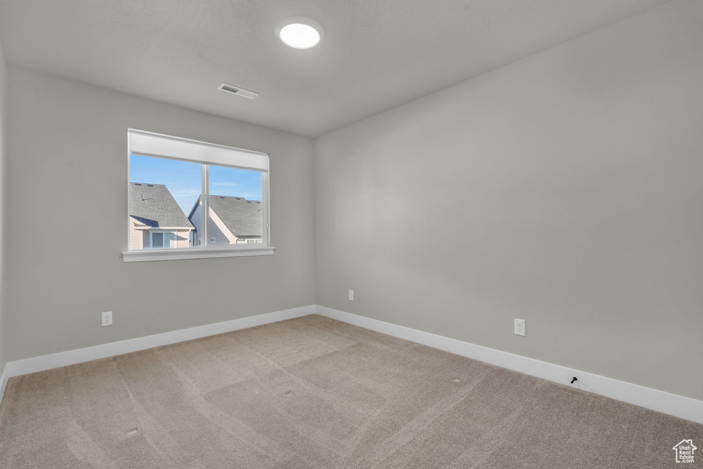 Carpeted empty room featuring visible vents and baseboards