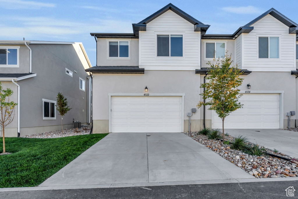 View of front facade with concrete driveway, central air condition unit, stucco siding, and an attached garage