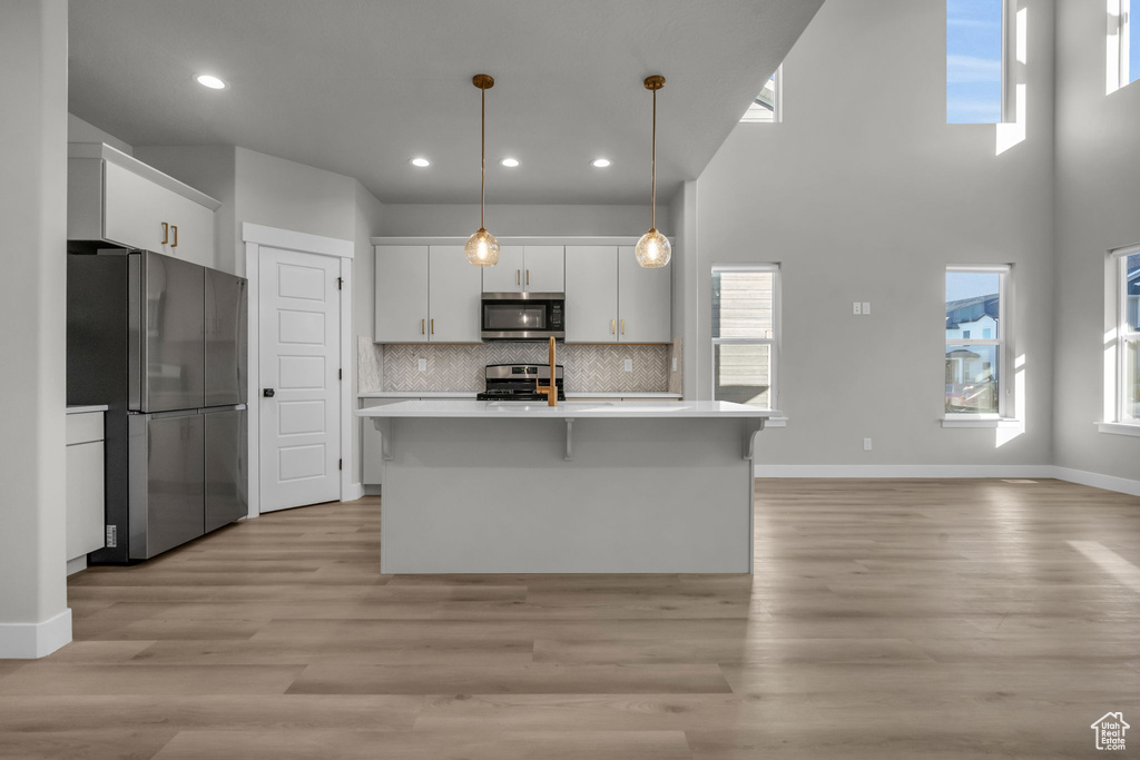 Kitchen featuring white cabinets, light countertops, decorative backsplash, and stainless steel appliances