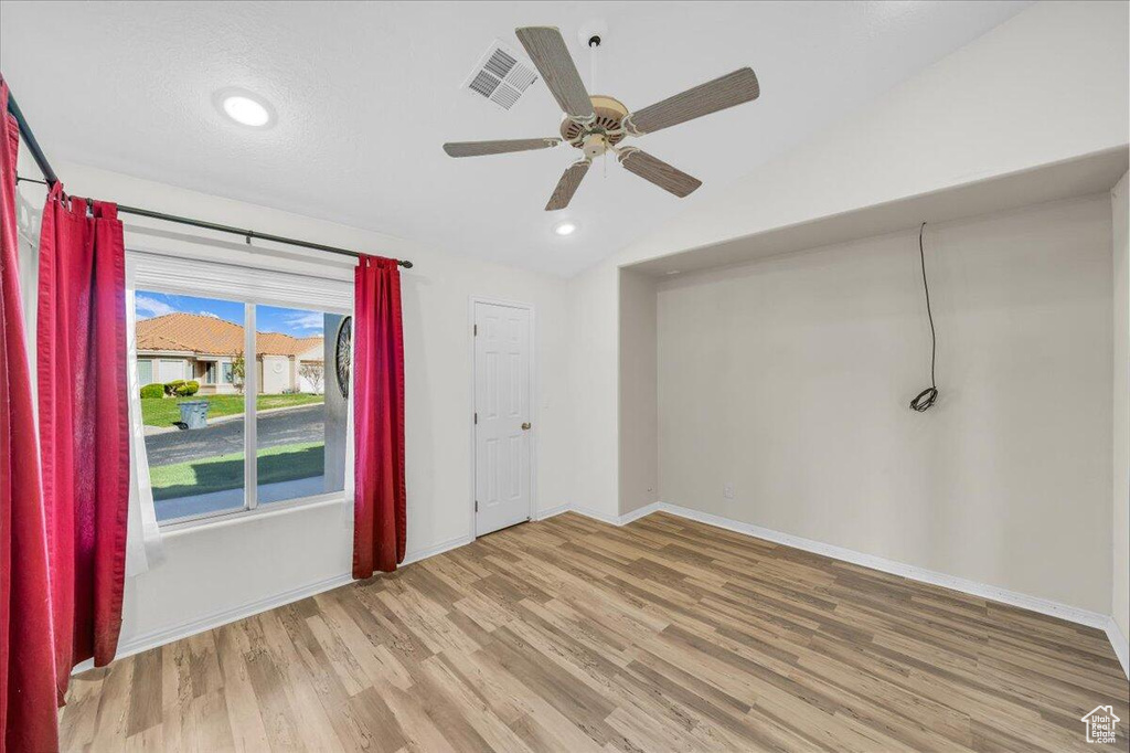 Unfurnished room with baseboards, vaulted ceiling, a ceiling fan, visible vents, and wood finished floors
