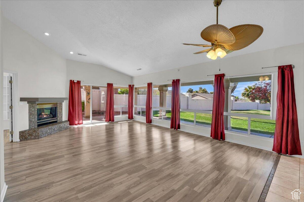 Unfurnished living room with visible vents, a textured ceiling, wood finished floors, and lofted ceiling