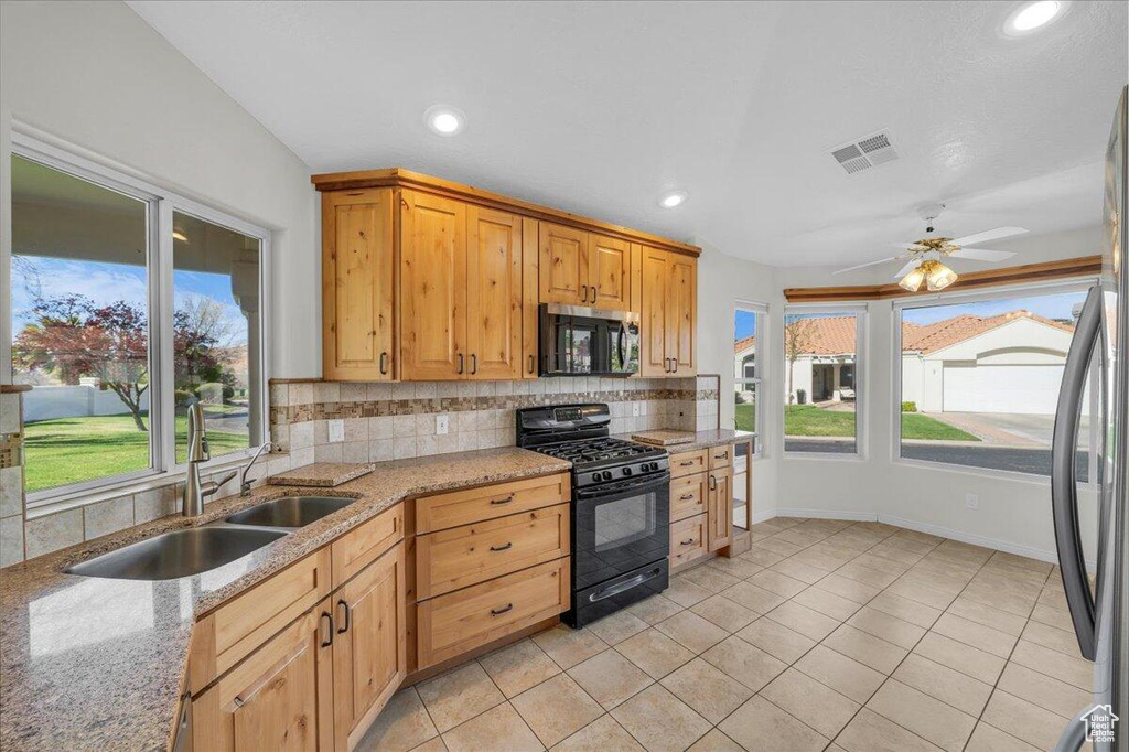 Kitchen with visible vents, a sink, freestanding refrigerator, black gas range, and backsplash