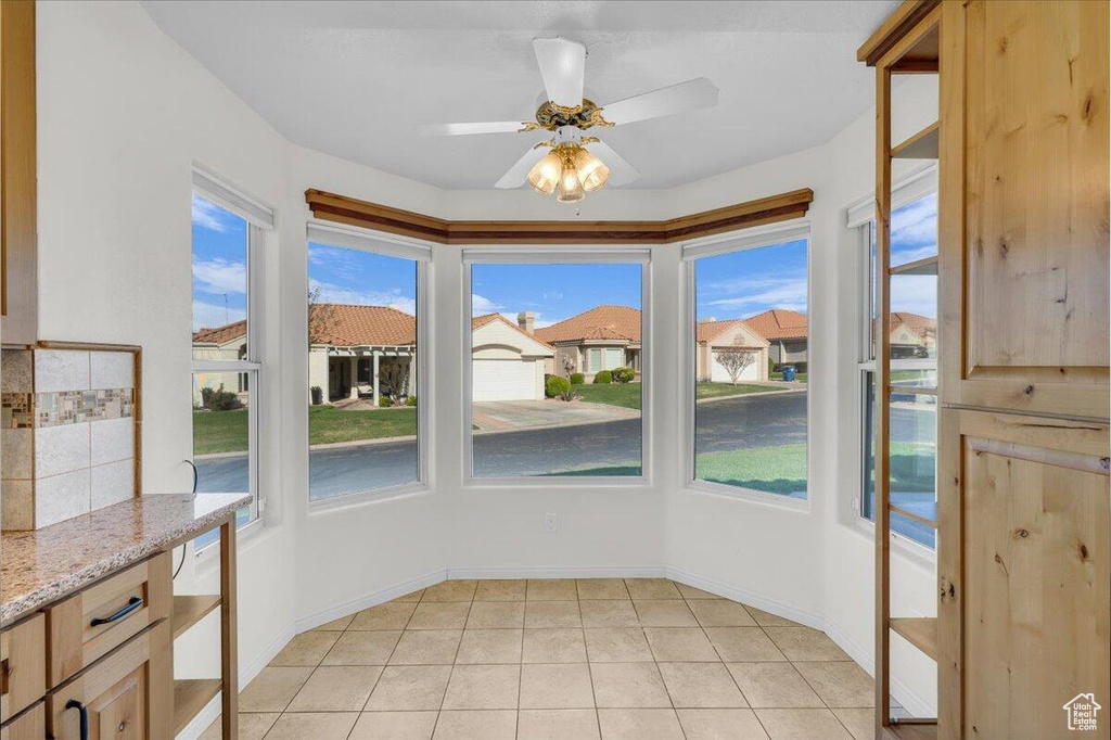 Unfurnished dining area with light tile patterned flooring, ceiling fan, baseboards, and a residential view