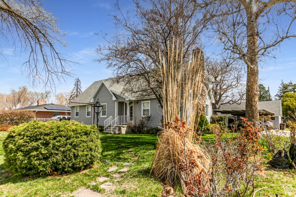 Back of property with a yard and a shingled roof