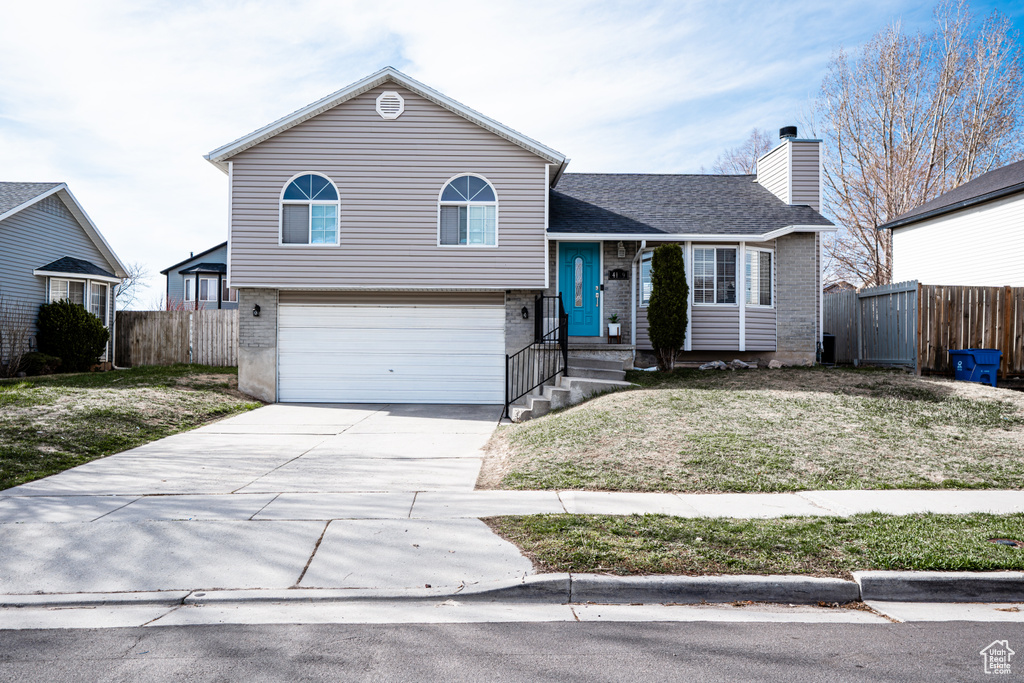 Tri-level home featuring brick siding, an attached garage, and concrete driveway