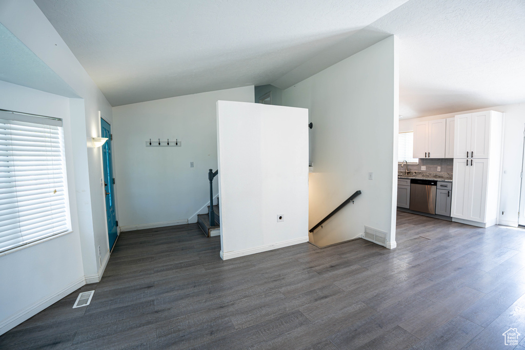 Unfurnished living room with dark wood-style floors, a sink, and baseboards