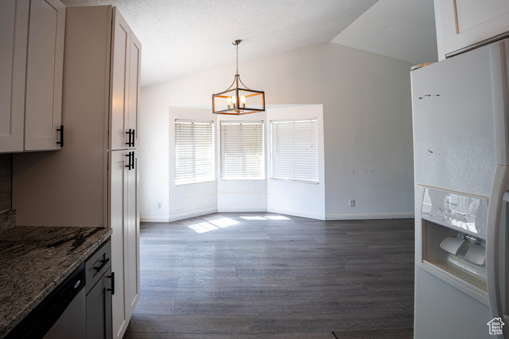Unfurnished dining area with a chandelier, lofted ceiling, dark wood finished floors, and baseboards