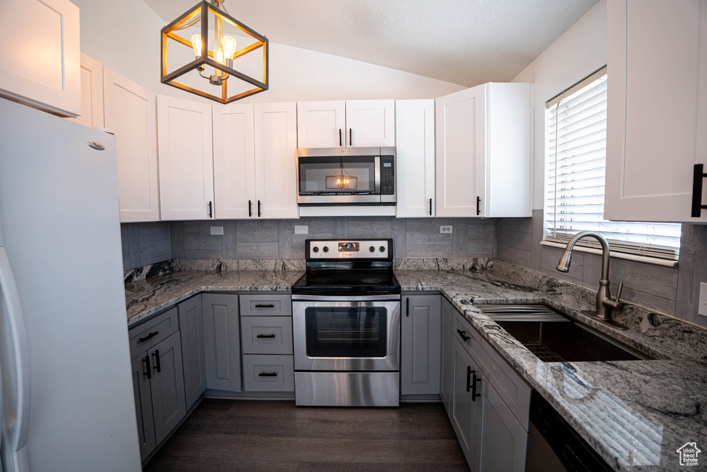 Kitchen with stainless steel appliances, a sink, vaulted ceiling, tasteful backsplash, and light stone countertops