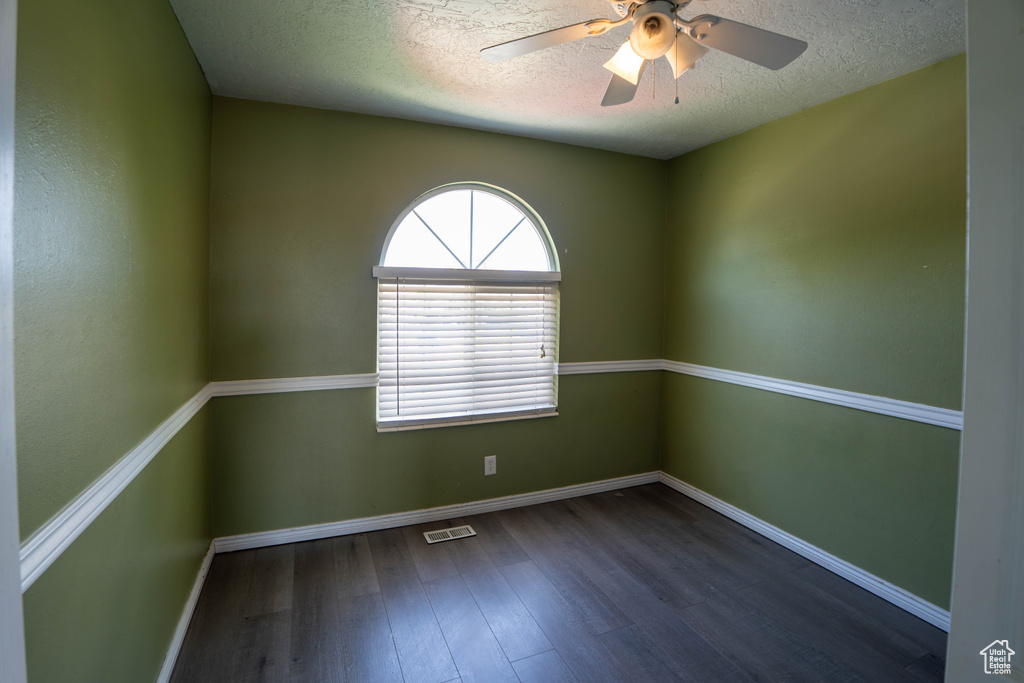 Empty room with wood finished floors, a textured ceiling, baseboards, and a ceiling fan