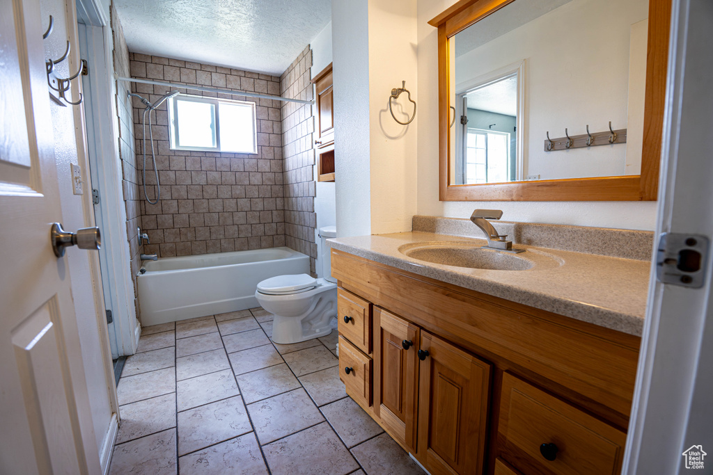 Full bathroom with toilet, vanity, shower / bathtub combination, and a textured ceiling
