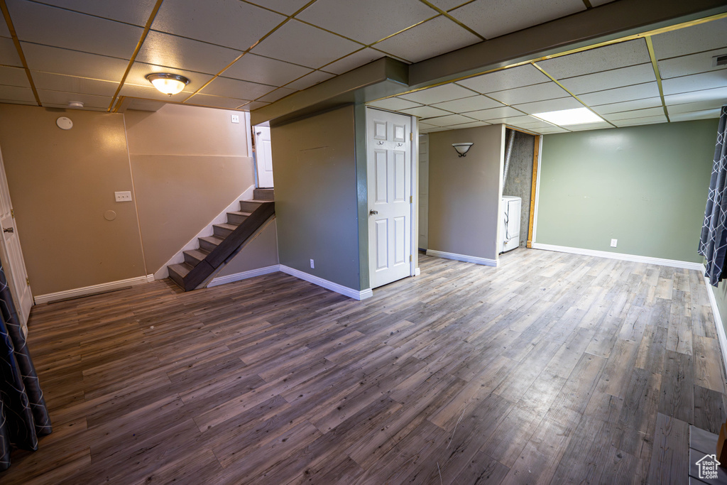Finished below grade area with a paneled ceiling, baseboards, washer / clothes dryer, and wood finished floors