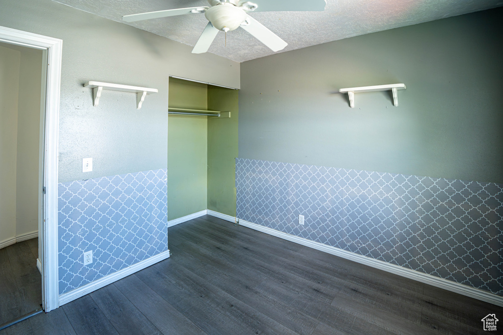 Unfurnished bedroom with wood finished floors, a closet, baseboards, ceiling fan, and a textured ceiling