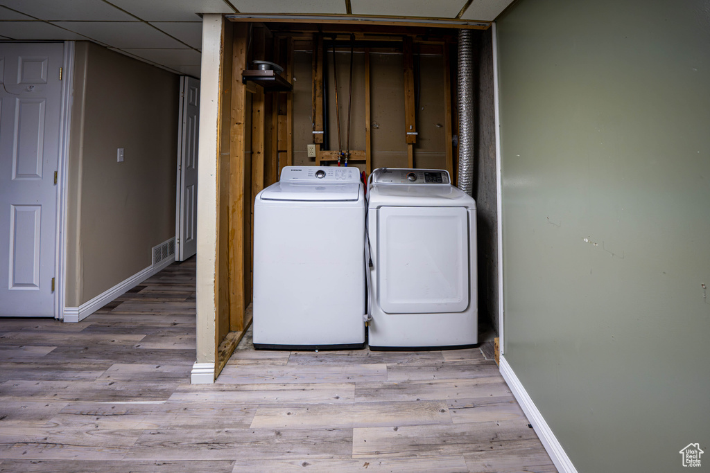 Laundry area with washing machine and clothes dryer, baseboards, and wood finished floors