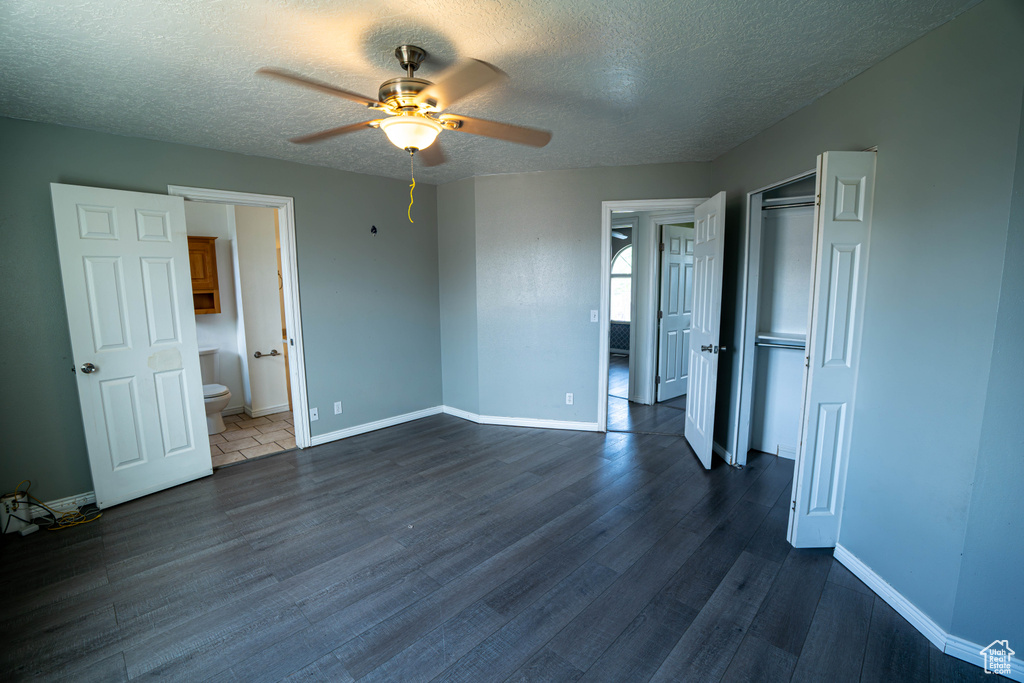 Unfurnished bedroom with dark wood-style flooring, a textured ceiling, baseboards, a closet, and a ceiling fan
