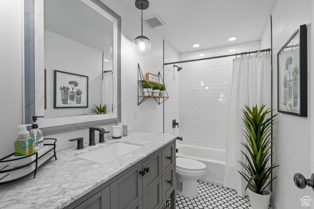 Full bath featuring vanity, tile patterned flooring, shower / bath combination with curtain, toilet, and visible vents