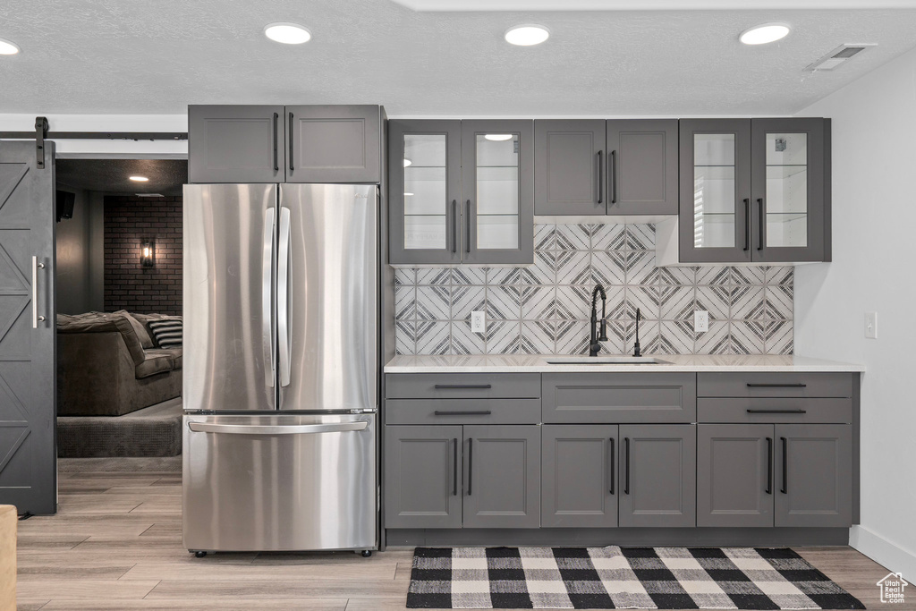 Kitchen featuring gray cabinets, light countertops, freestanding refrigerator, visible vents, and a sink