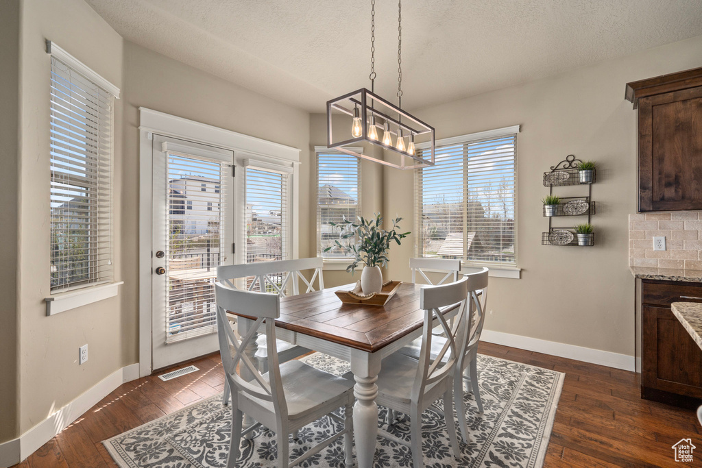 Dining area featuring a notable chandelier, a textured ceiling, visible vents, and dark wood finished floors
