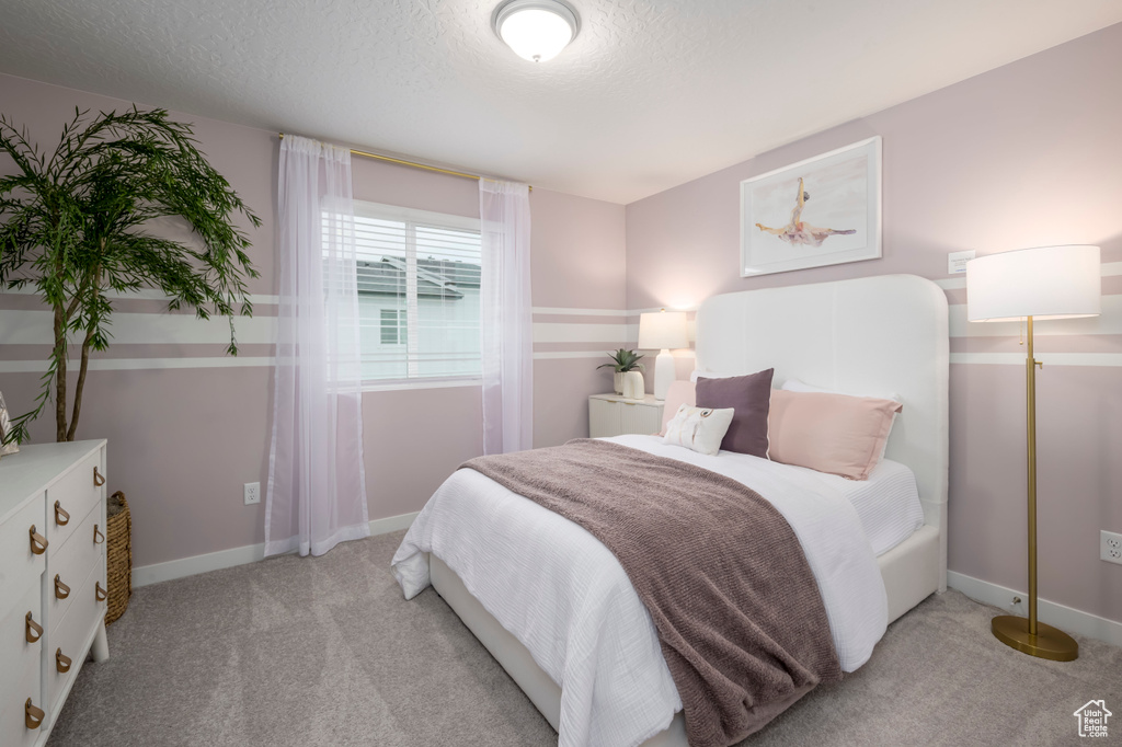 Bedroom featuring baseboards, light carpet, and a textured ceiling