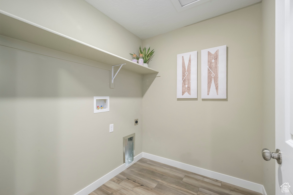Clothes washing area with laundry area, hookup for an electric dryer, washer hookup, light wood finished floors, and baseboards