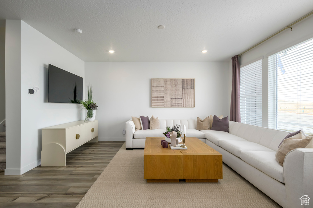 Living area with a textured ceiling, light wood finished floors, baseboards, and recessed lighting
