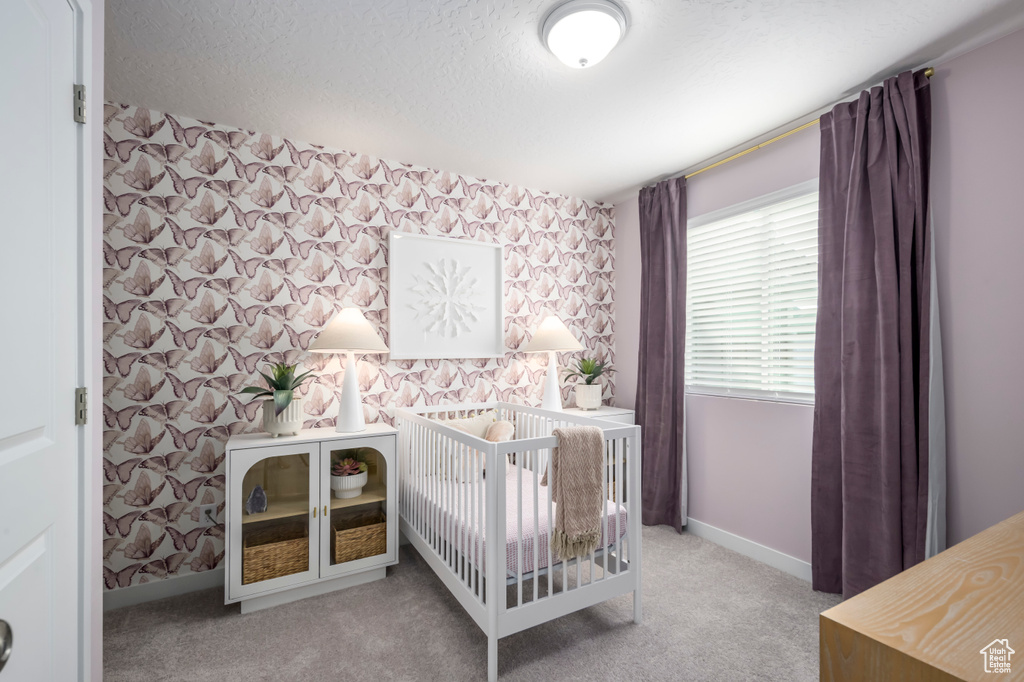 Bedroom with baseboards, a textured ceiling, wallpapered walls, and carpet floors