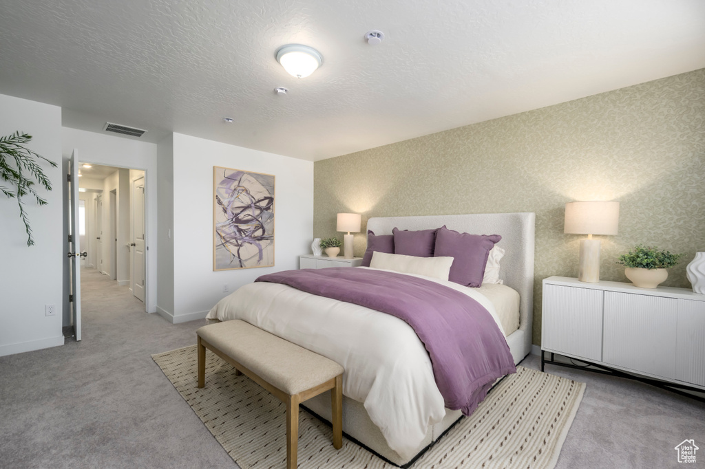 Bedroom featuring a textured ceiling, visible vents, light carpet, wallpapered walls, and baseboards