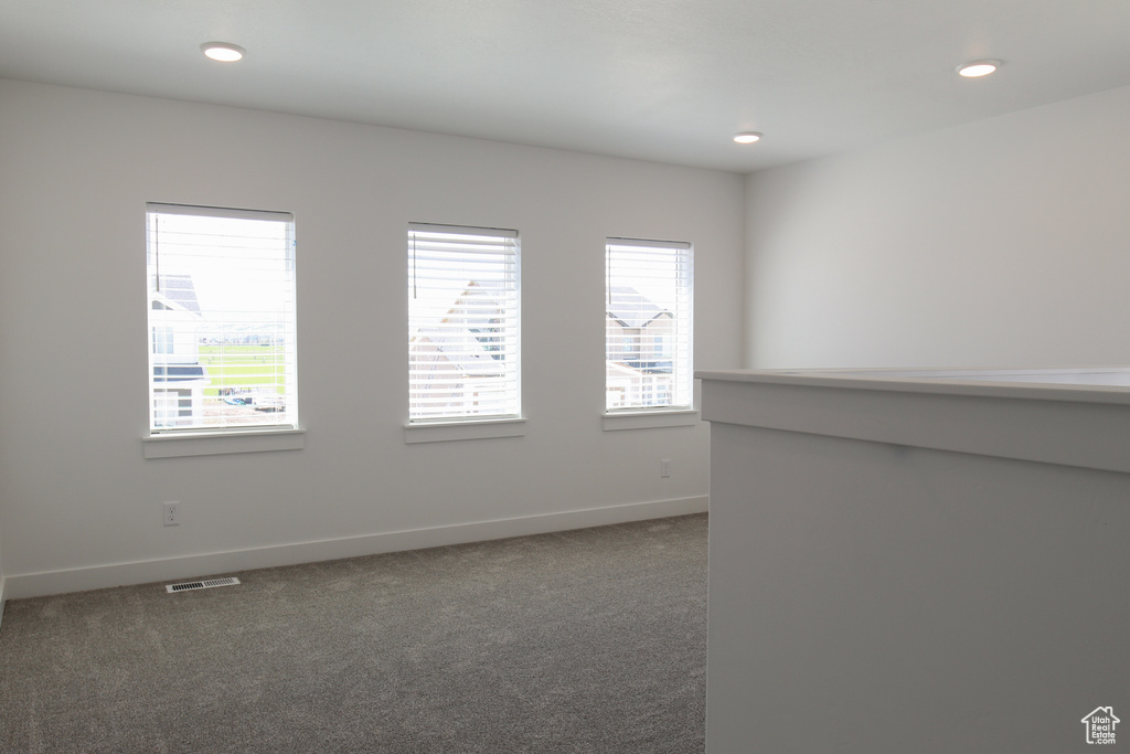 Spare room with visible vents, baseboards, dark carpet, and recessed lighting