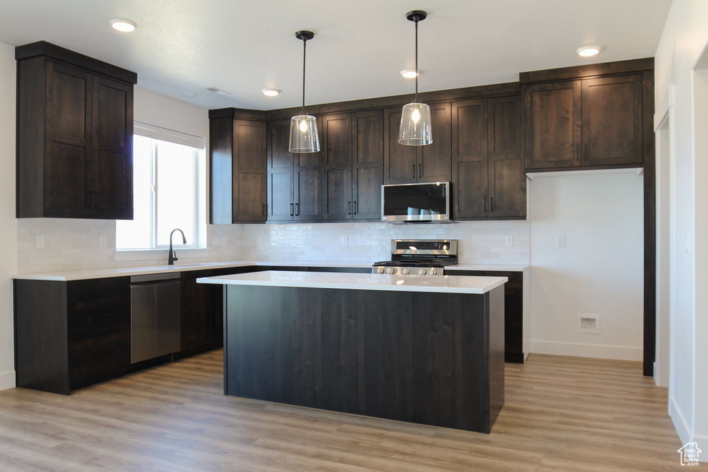 Kitchen with stainless steel appliances, backsplash, baseboards, and dark brown cabinets