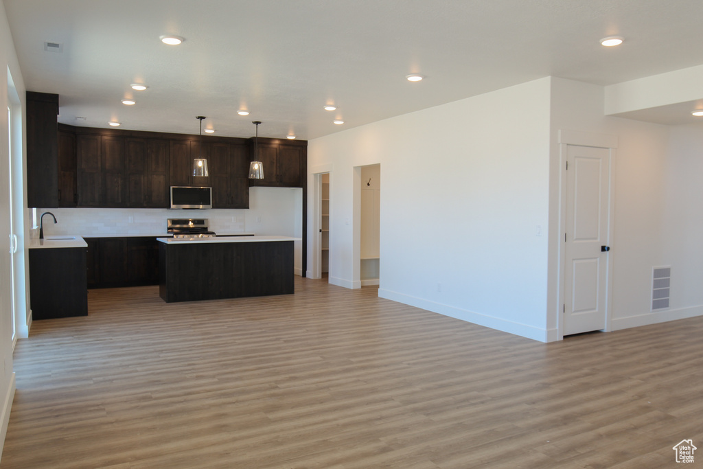 Kitchen featuring baseboards, light wood finished floors, visible vents, open floor plan, and stainless steel appliances