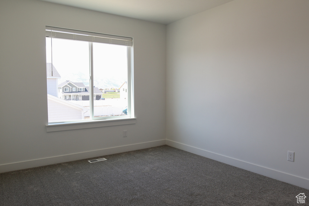 Unfurnished room featuring carpet flooring, visible vents, and baseboards