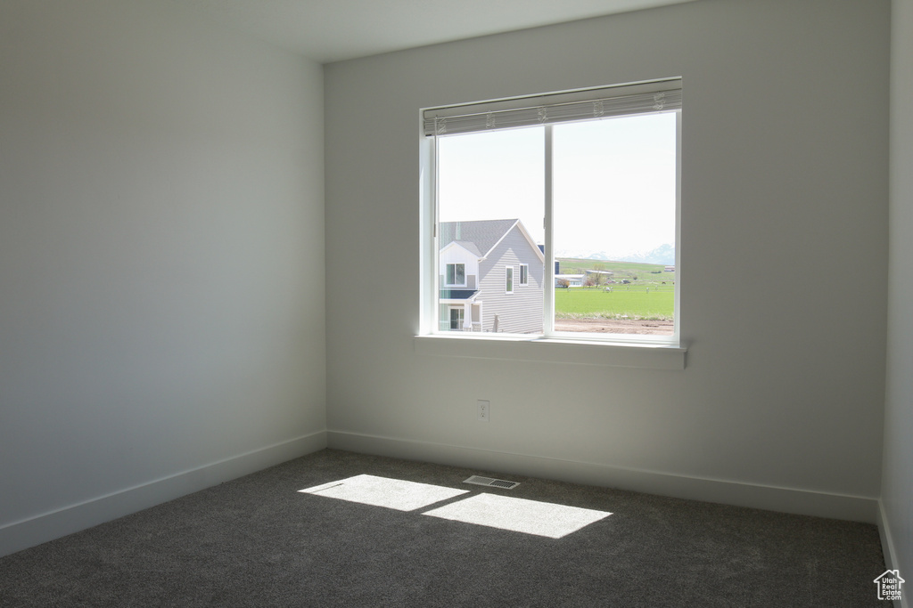 Empty room featuring carpet, baseboards, and visible vents