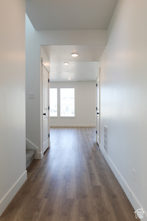 Hallway featuring stairs, visible vents, baseboards, and dark wood-style floors