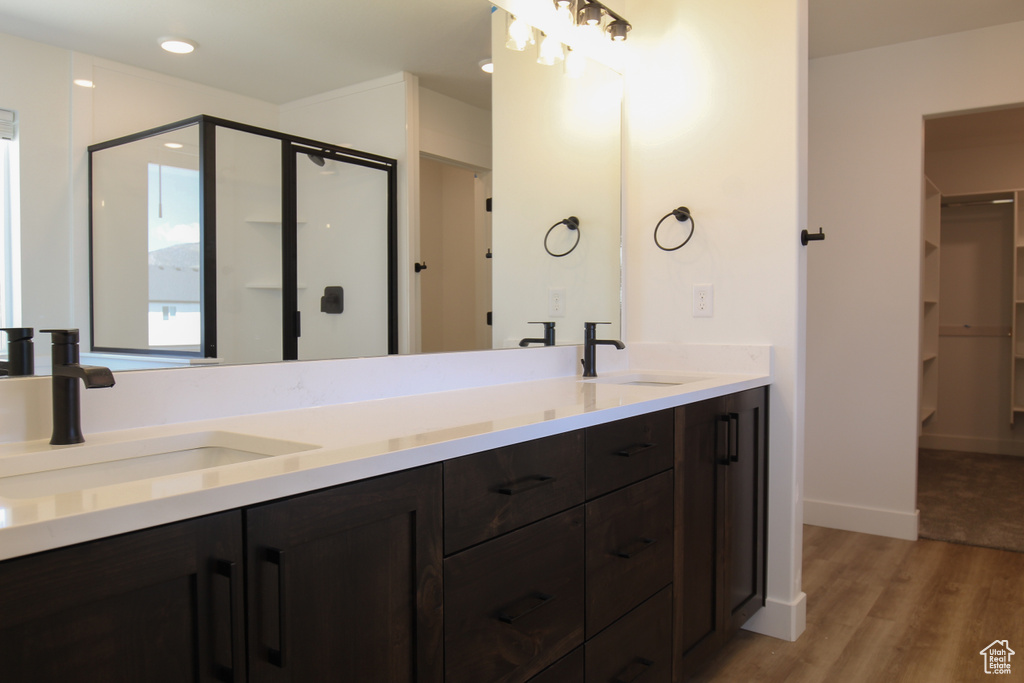 Bathroom with double vanity, wood finished floors, a shower stall, and a sink