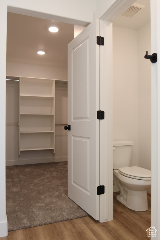 Bathroom with toilet, visible vents, wood finished floors, and recessed lighting