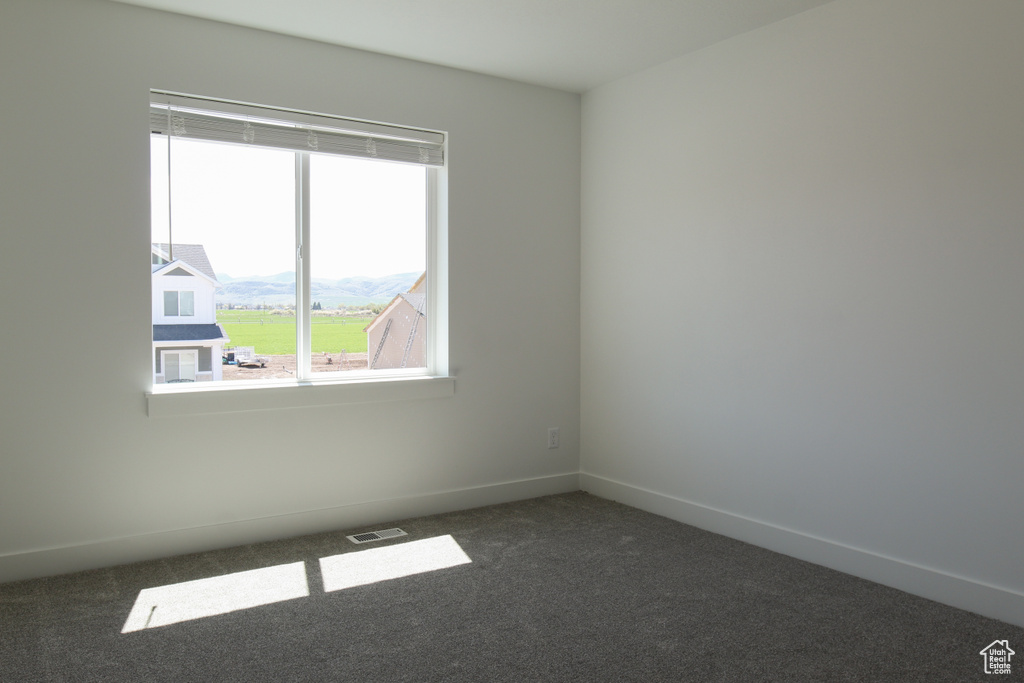 Unfurnished room with baseboards, visible vents, and dark carpet