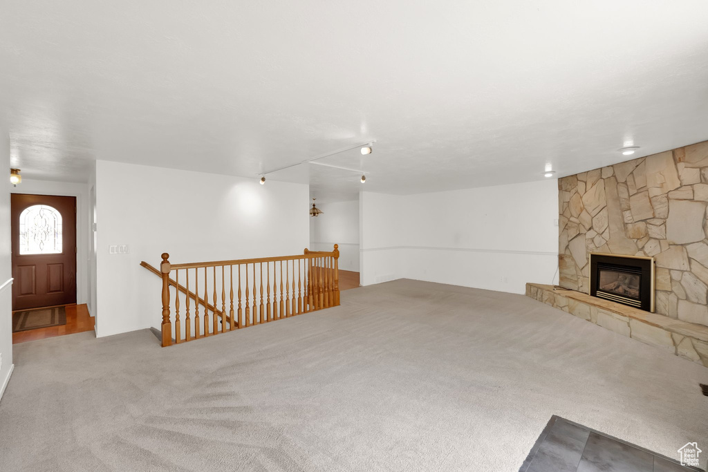 Unfurnished living room with carpet floors and a stone fireplace
