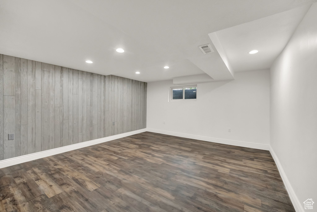 Below grade area featuring visible vents, baseboards, recessed lighting, dark wood-type flooring, and wood walls