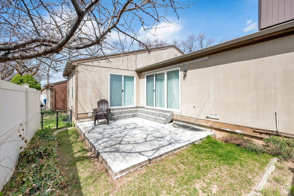 Rear view of house featuring fence and a patio