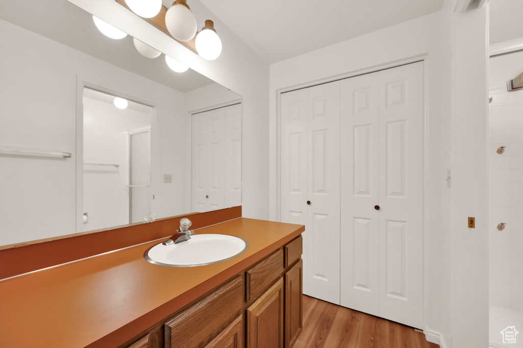 Bathroom with vanity, a closet, a tile shower, and wood finished floors
