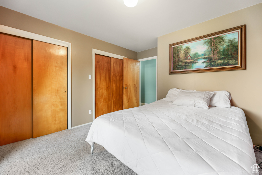 Carpeted bedroom featuring multiple closets and baseboards