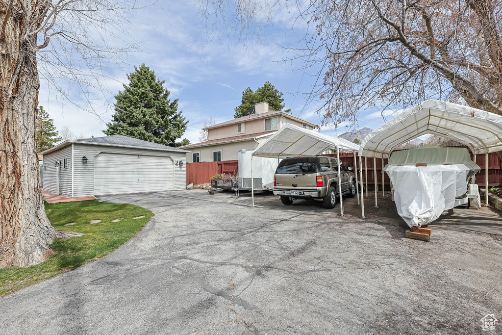Exterior space with a detached carport, a garage, and fence
