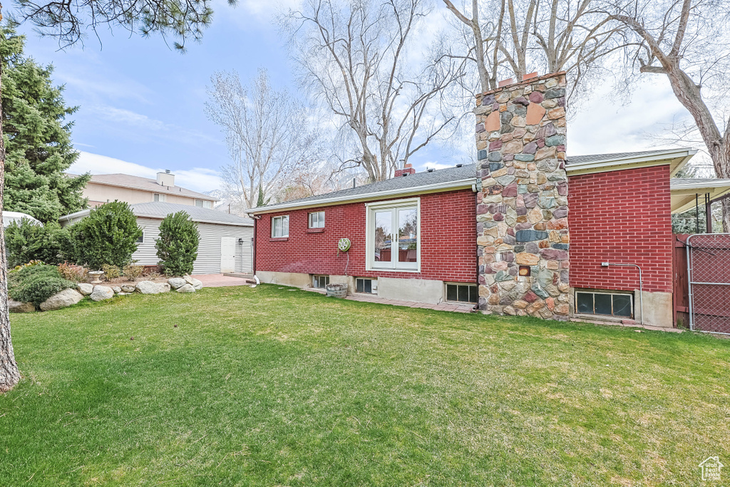 Back of property featuring an outbuilding, a chimney, brick siding, and a yard