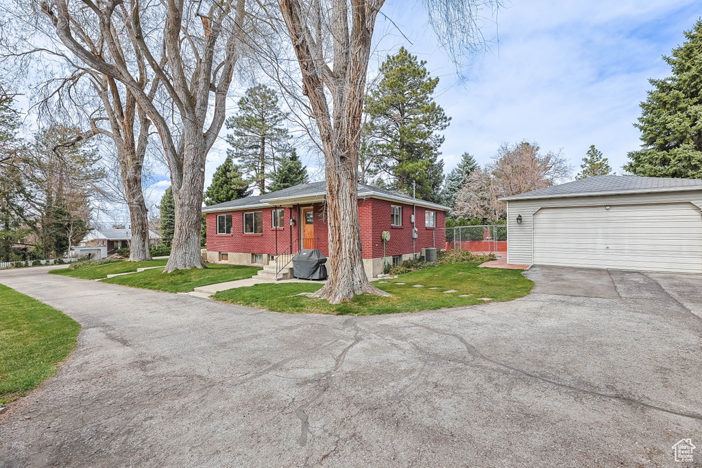 View of home\\\'s exterior featuring central AC, brick siding, a lawn, and a garage