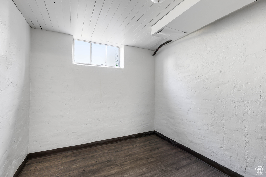 Basement with dark wood-style flooring, wood ceiling, and baseboards
