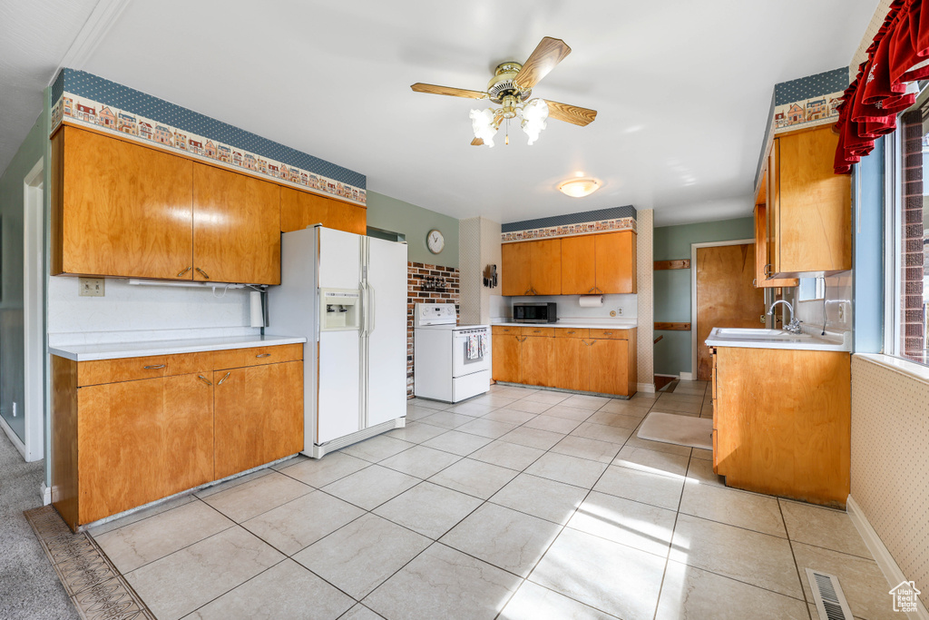 Kitchen featuring a sink, light countertops, ceiling fan, white appliances, and brown cabinets