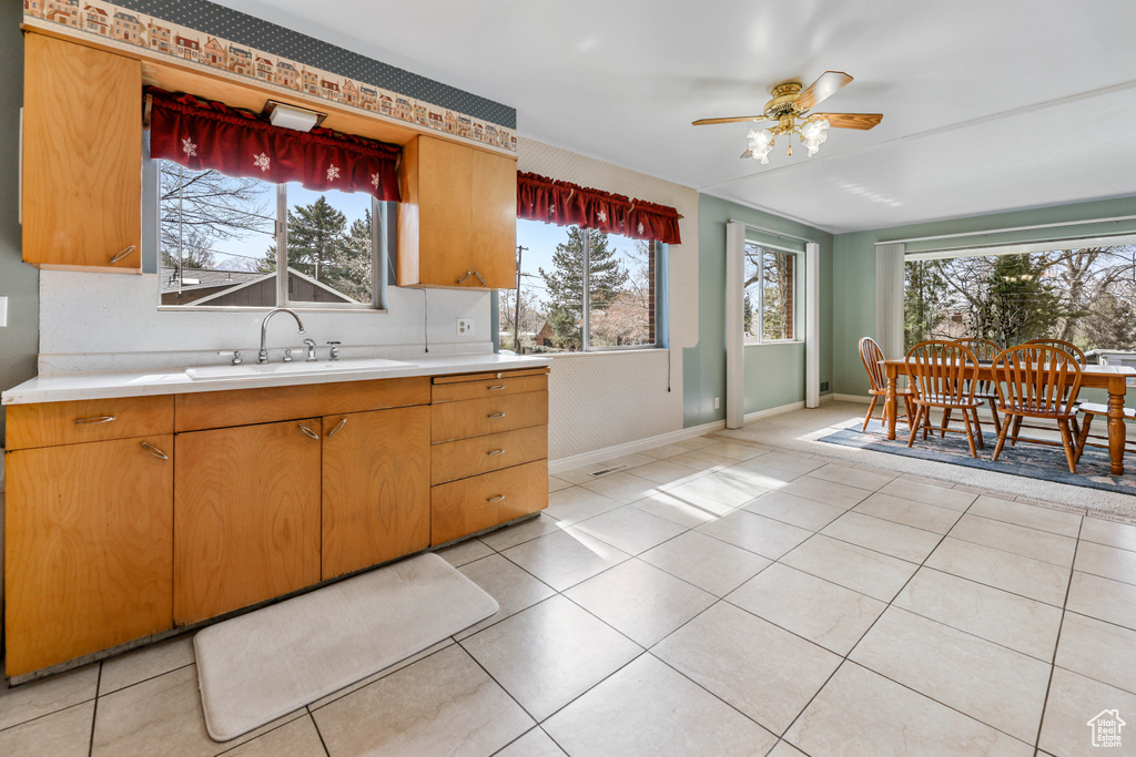 Kitchen featuring a sink, light tile patterned floors, light countertops, and a ceiling fan