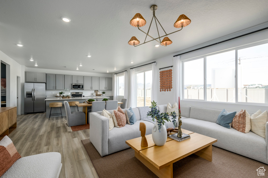 Living room featuring a chandelier, light wood-style floors, and recessed lighting