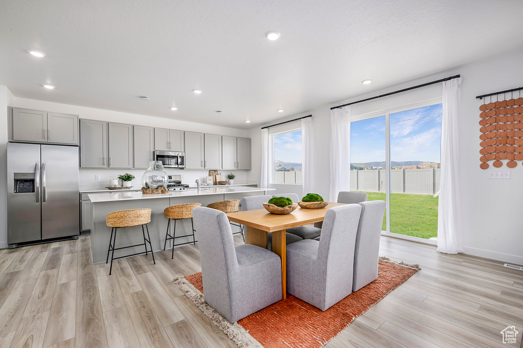 Dining area with baseboards, light wood finished floors, and recessed lighting
